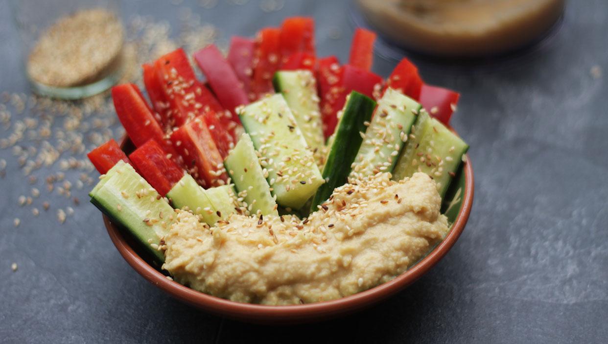 Köstlicher Hummus mit Gemüsesticks und geröstetem Sesam